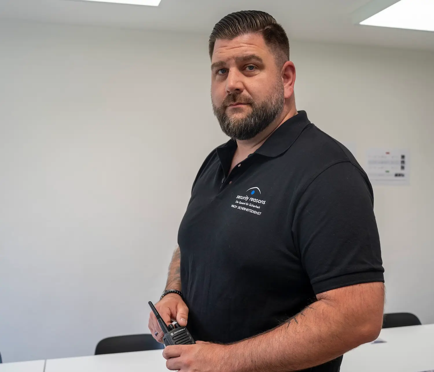 Mitarbeiter von security reasons im Poloshirt mit Firmenlogo hält ein Funkgerät in der Hand