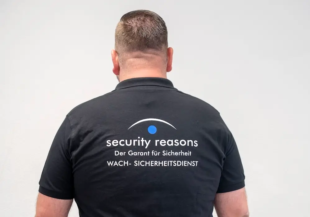 Mitarbeiter von security reasons im Poloshirt mit Firmenlogo, von hinten fotografiert