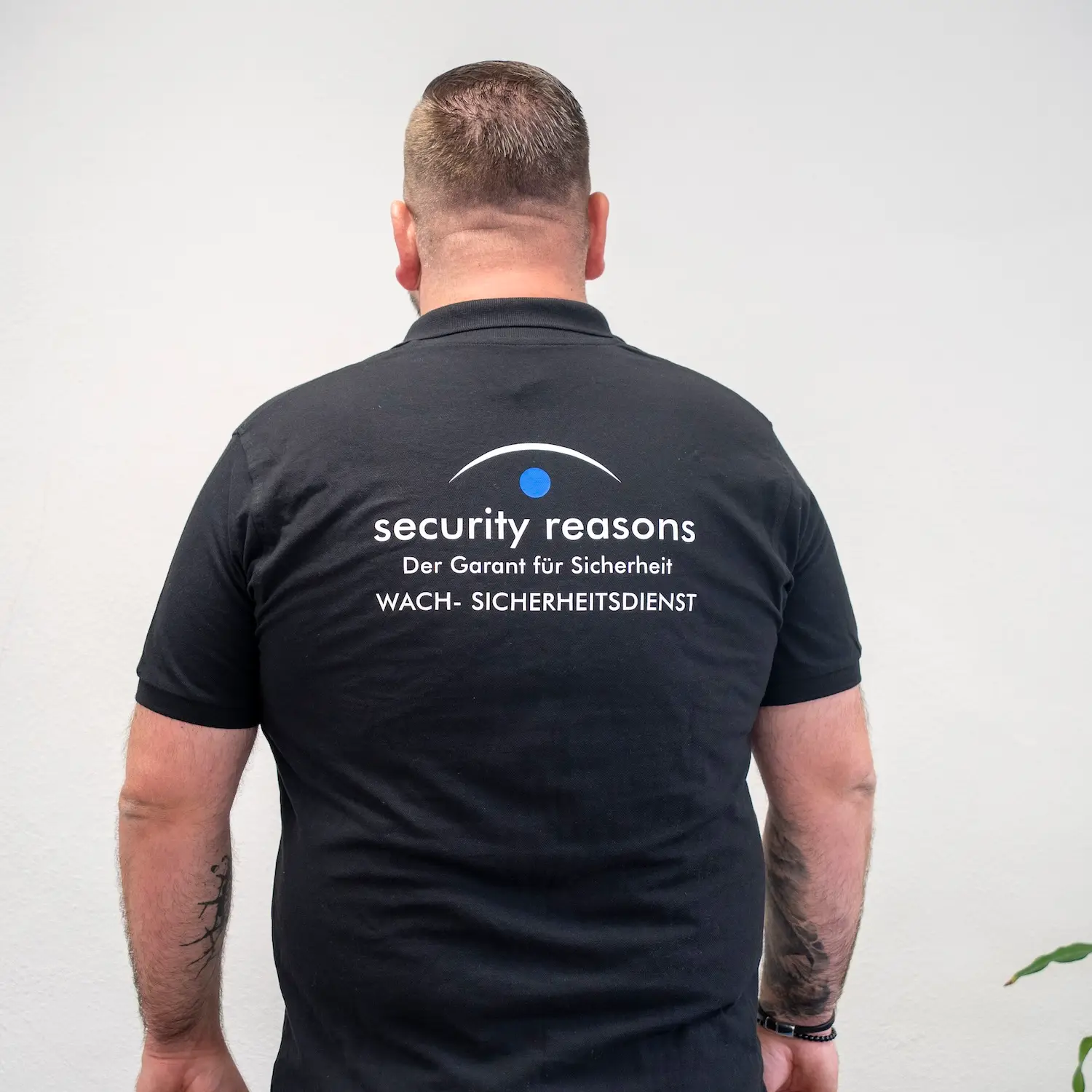 Mitarbeiter von security reasons im Poloshirt mit Firmenlogo, von hinten fotografiert