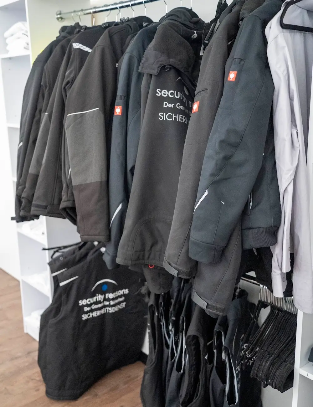 Einsatzjacken und Warnwesten mit dem Logo von security reasons auf einer Kleiderstange
