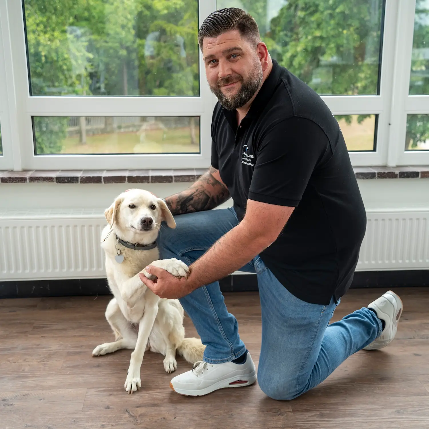 Mitarbeiter von security reasons kniet neben einem hellen Hund